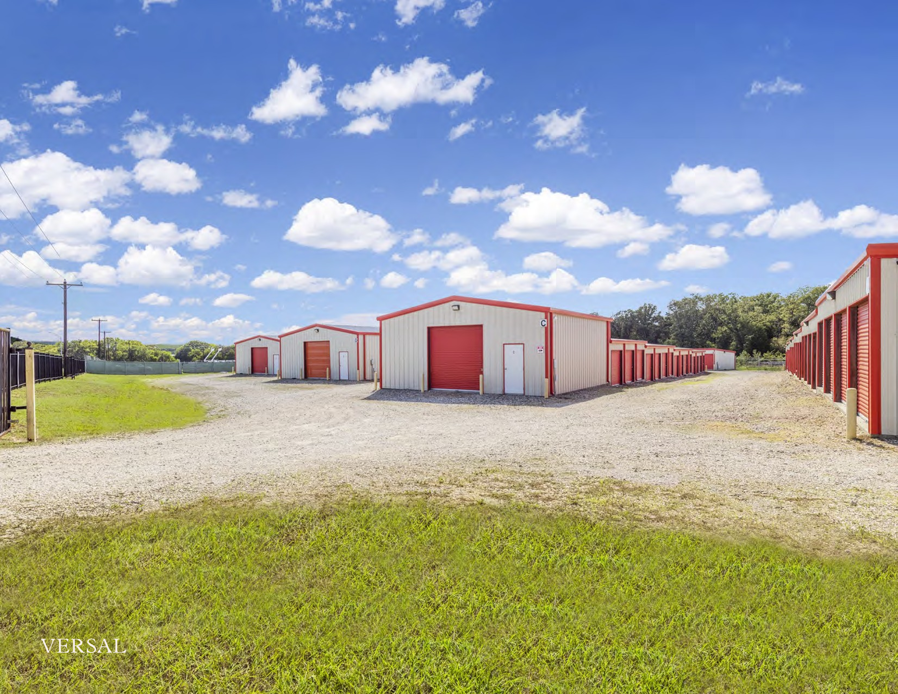 Wide view of secure drive-up self-storage units with red roll-up doors at Athens Secure Storage & Parking in Athens, TX under a bright blue sky.